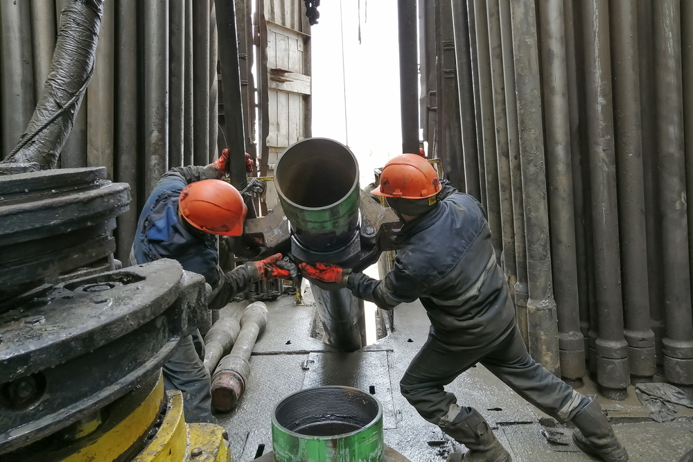 Drilling crew operating rig equipment with safety gear during on-site training procedures