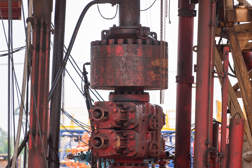Blowout preventer (BOP) assembly installed on an oil drilling rig, used for controlling well pressure and preventing uncontrolled fluid release during drilling operations.